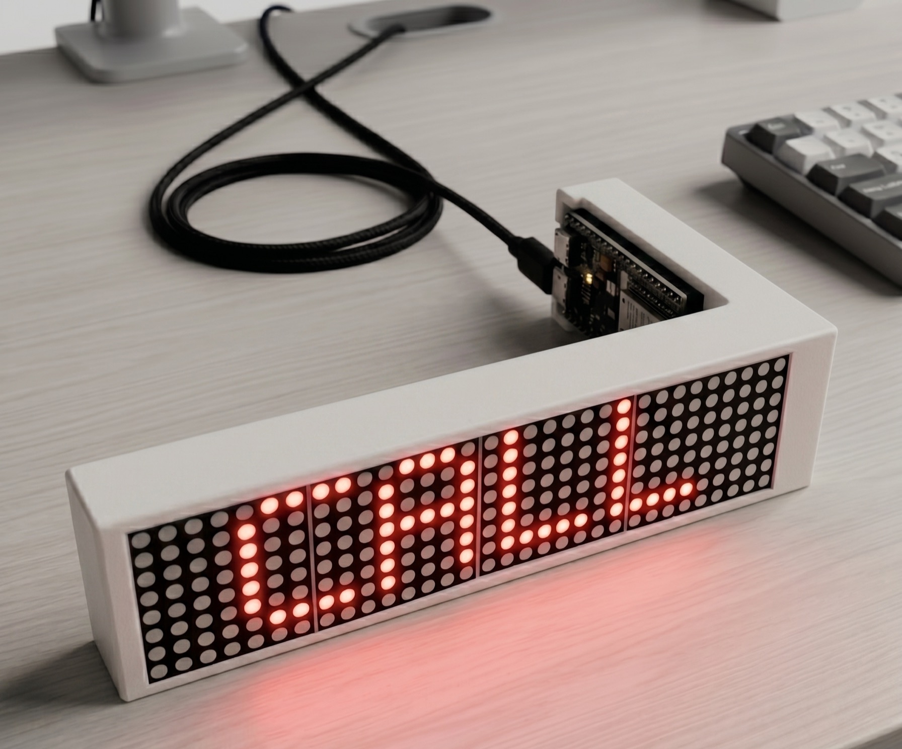 The LED Ticker on a desk in its white case, its red dot-matrix display reading CALL, wired to an ESP32-S3 board over a braided USB-C cable.